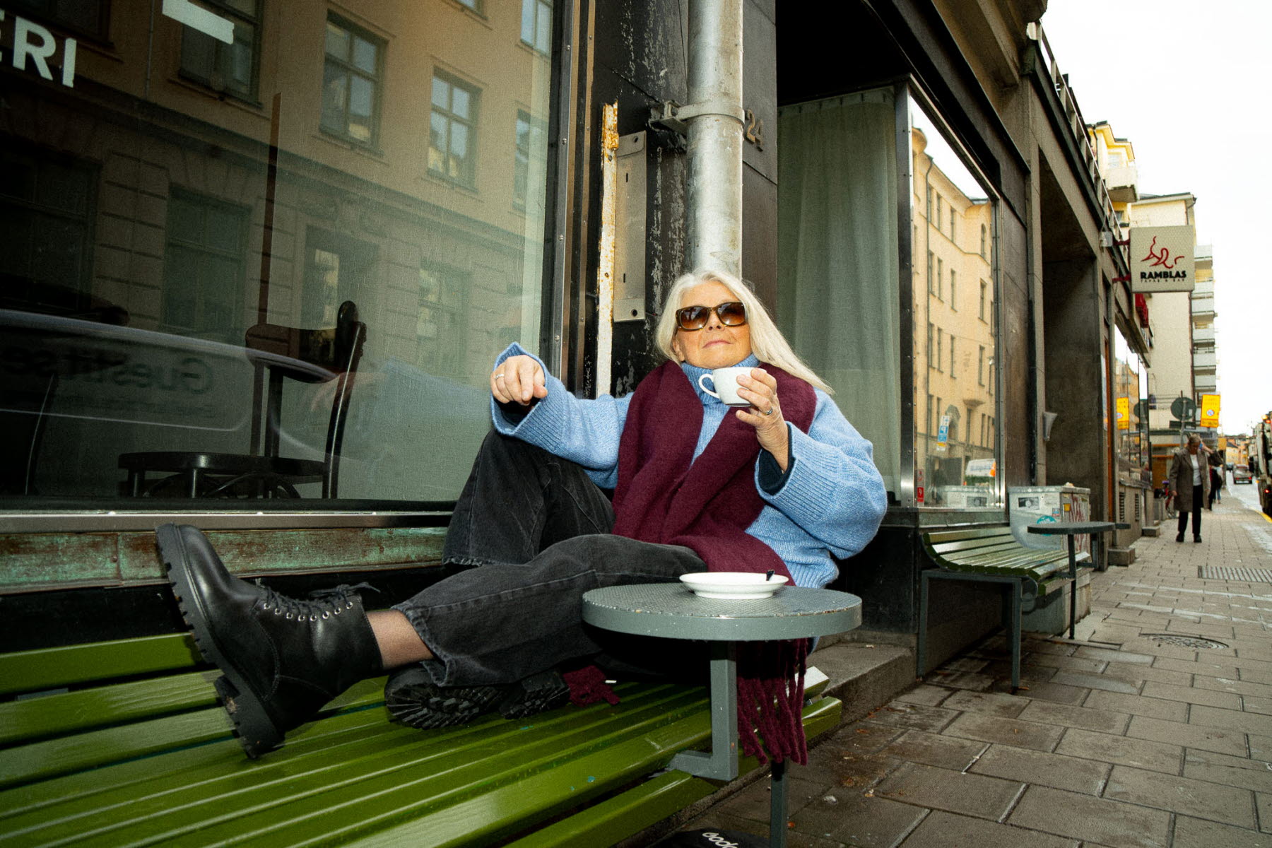 kvinna på bänk med en kopp kaffe i handen