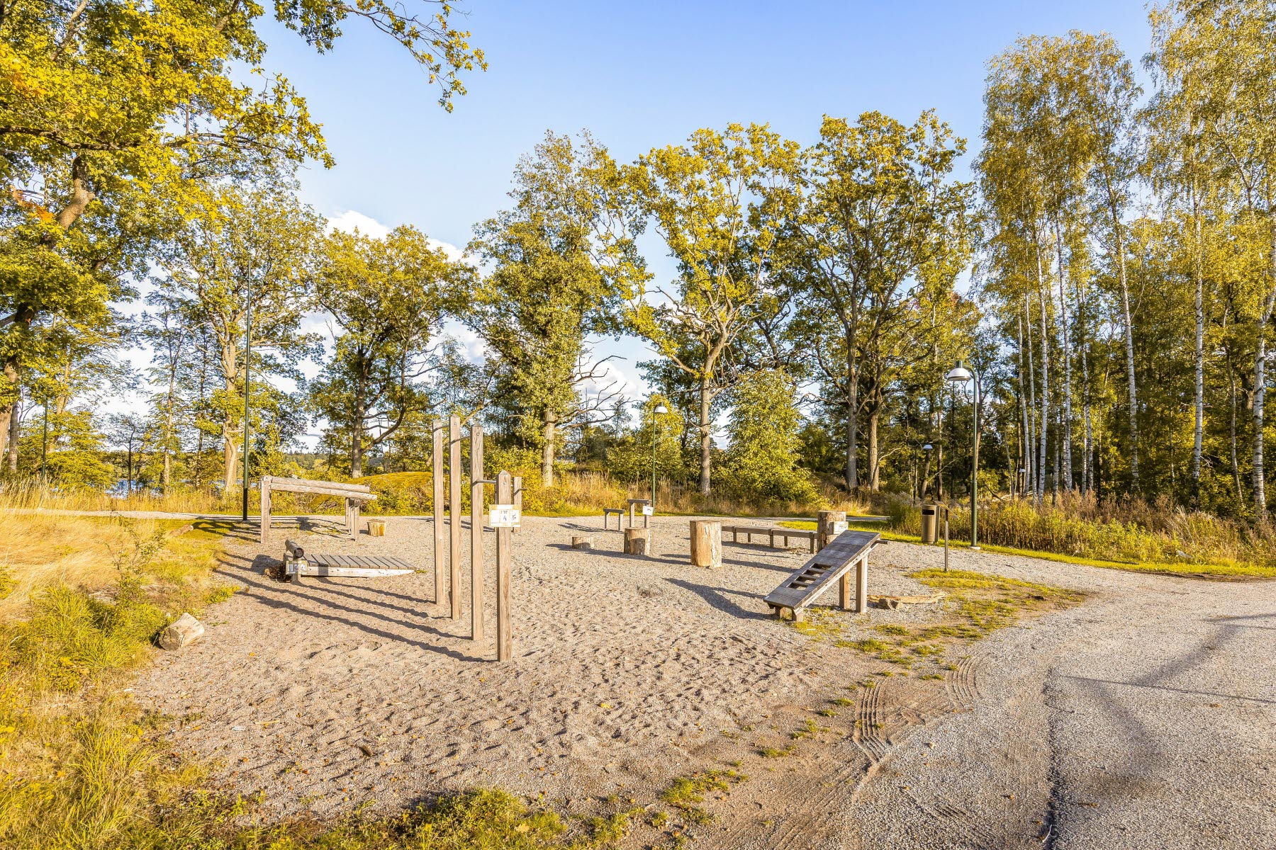 Områdesbild sensommar. Utegym på grus.