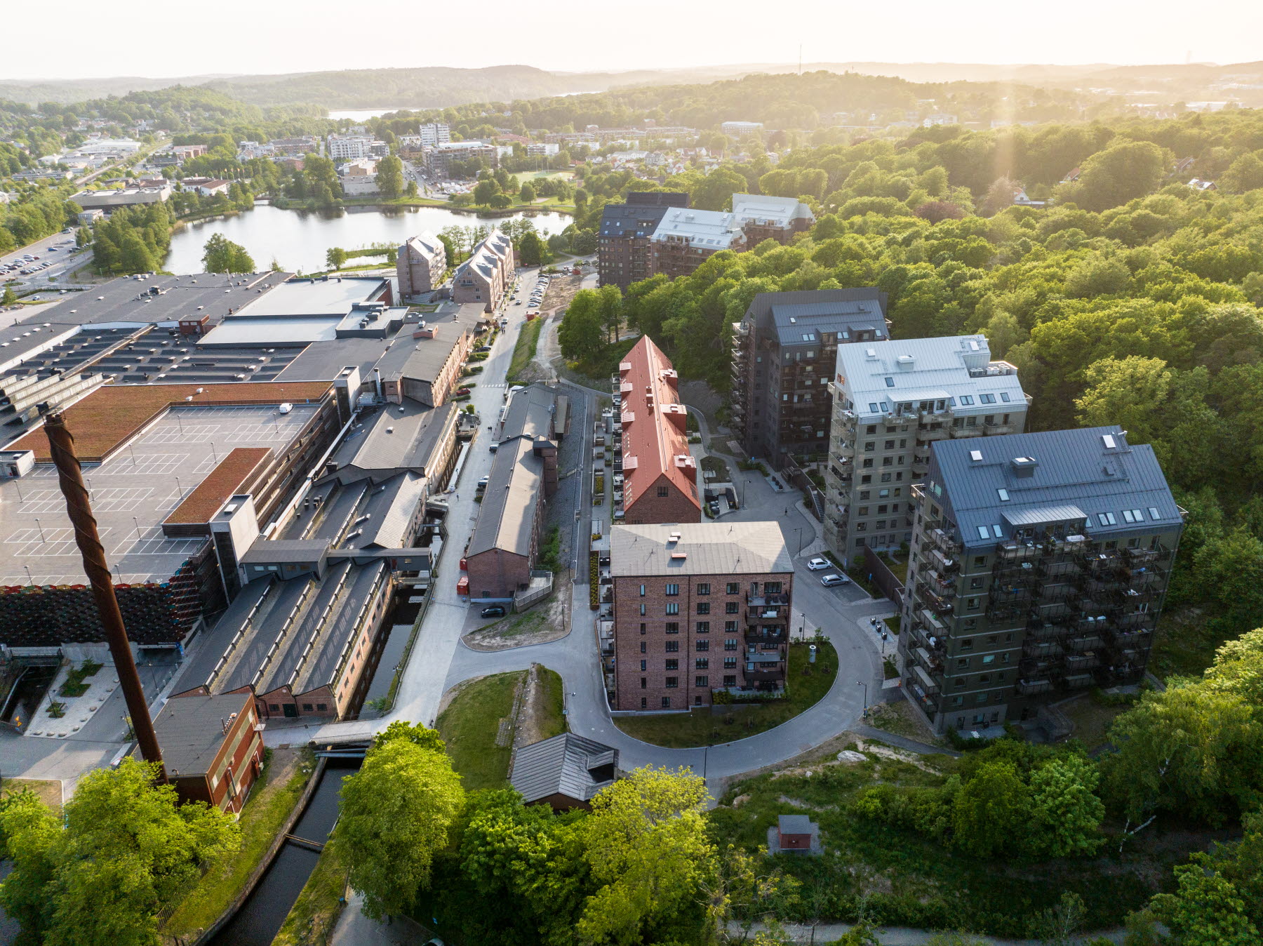 En drönarbild på en sommarkväll i mölnlyckefabriker. gröna träd och bostadshus.
