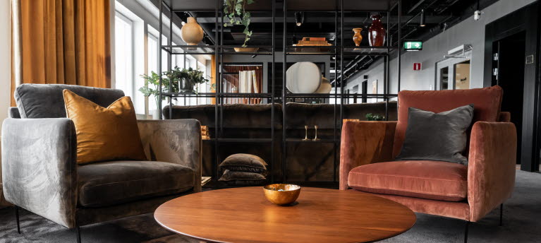 Ett stort öppet kontorslandskap med två grå och röds sammetsfotöljer i förgrunden