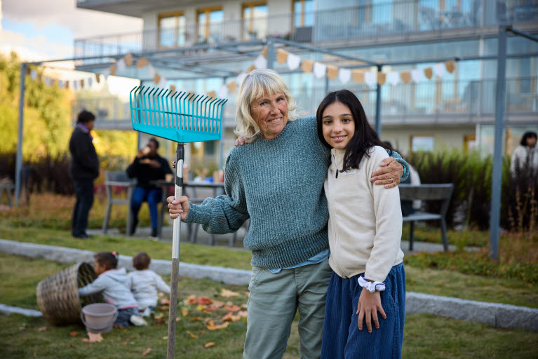 Grannar som umgås på städdag, en äldre kvinna som håller om en ung tjej