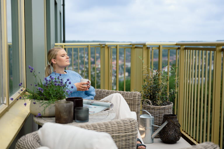 En kvinna sitter på en balkong med en kopp kaffe