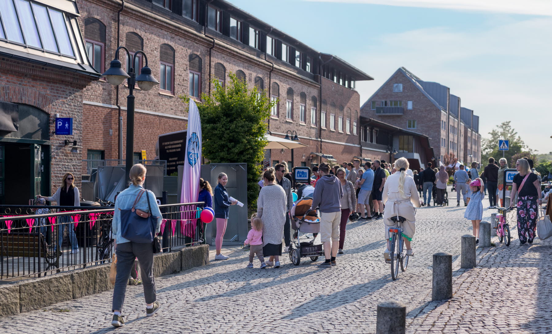 Sommarkväll längst med bruksgtan där folk kommer gåendes och på cykel