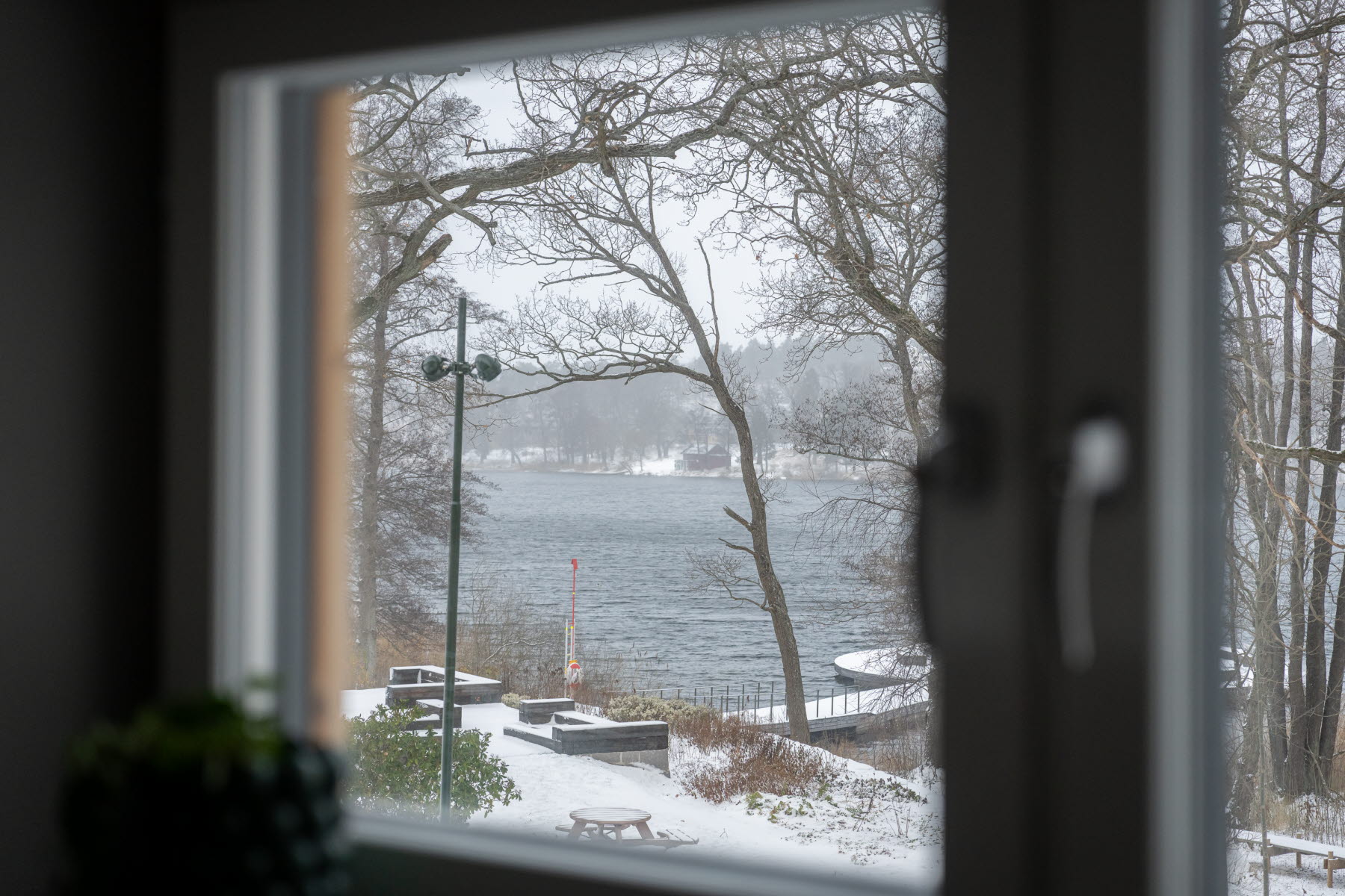 Inzoomad bild med utsikt mot vattnet och bryggan från sovrumsfönster.
