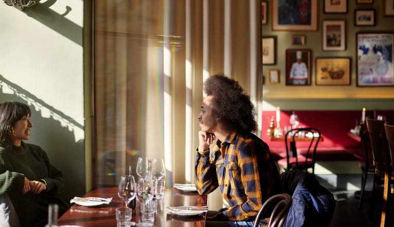 Två personer sitter vid ett dukat bord på en restaurang.