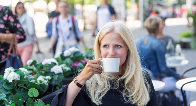 En ung kvinna drick kaffe på en uteservering