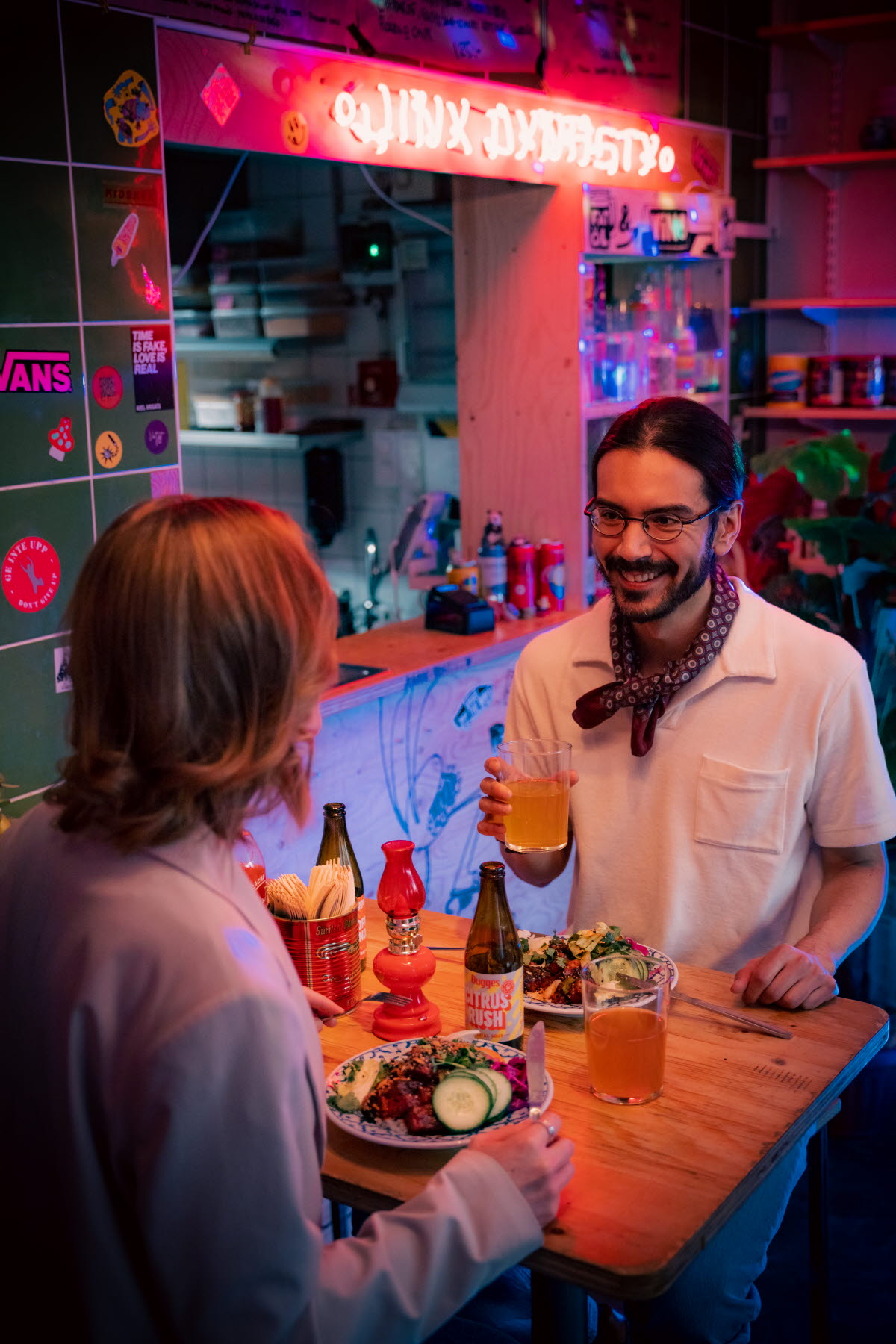 kille och tjej äter och dricker vid restaurangbord. 