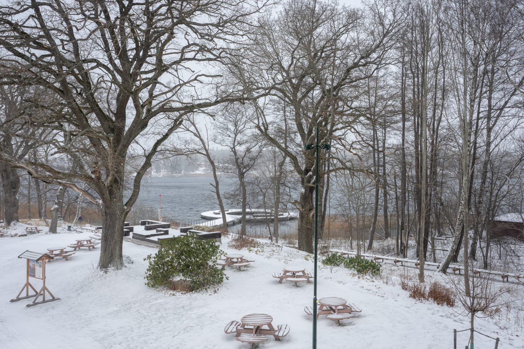 Utsikt från balkongen mot vattnet och badbryggan. Marken är täckt av snö.