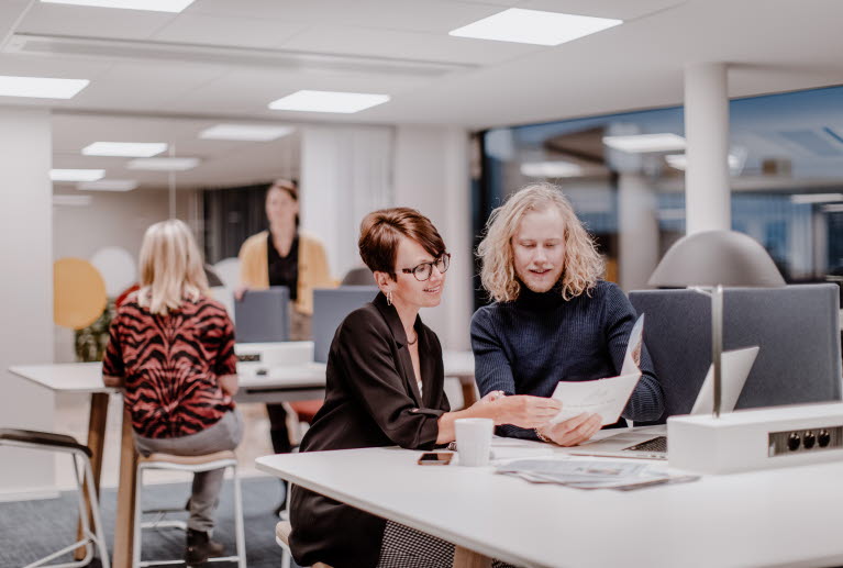 Fyra personer arbetar i ett öppet kontorslandskap.