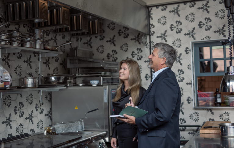 En kvinna och en man står och pratar i ett restaurangkök