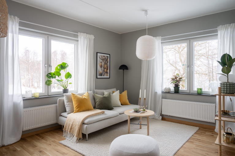 Vardagsrum i hörnläge med fönster på båda sidorna om soffan.